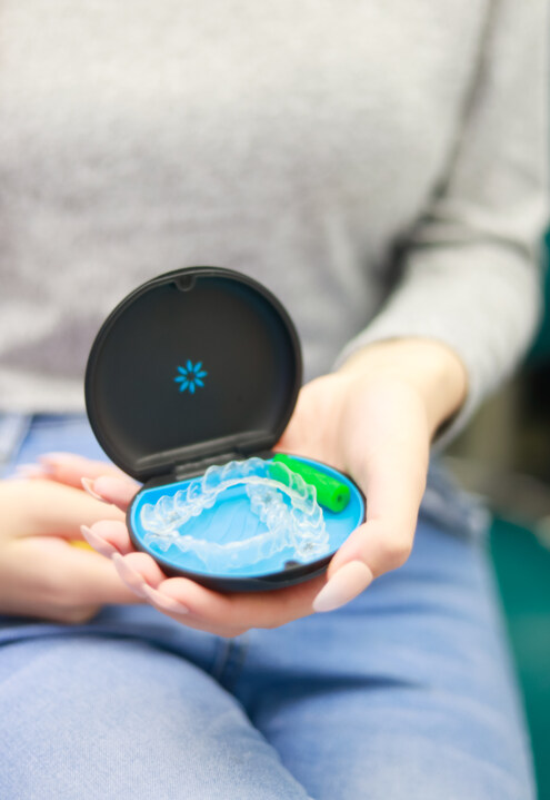 A patient holding their clear aligners in a travel case